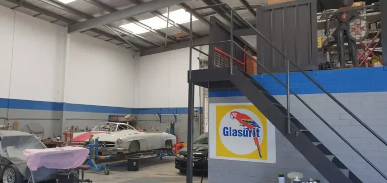 Interior view of an auto repair workshop with cars, lifts, and blue trim walls