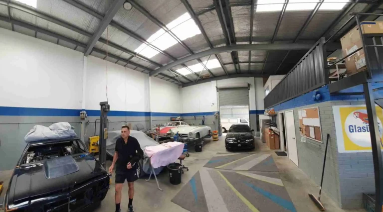 Wide view of an auto repair workshop with cars and blue painted wall trim