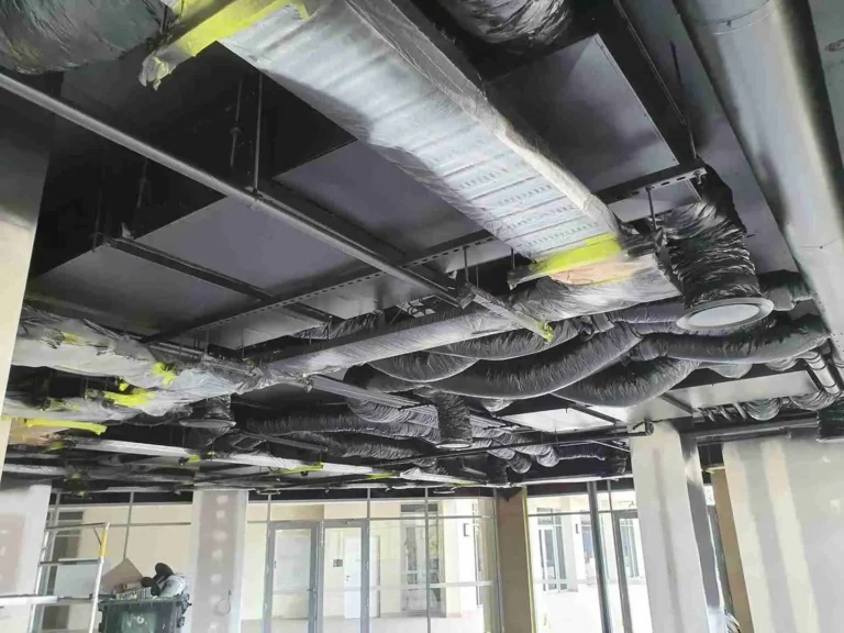 Industrial interior with black painted exposed ceiling pipes and ductwork