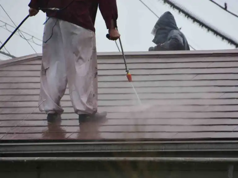 Professional pressure washing a metal roof before painting