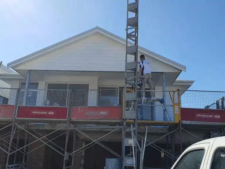 Painter standing on scaffolding working on a house exterior