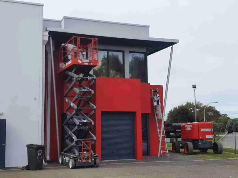 Red commercial building with scissor lift equipment outside