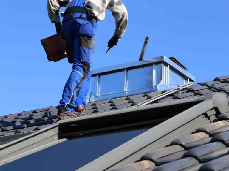 Worker in blue overalls inspecting roof tiles on a house