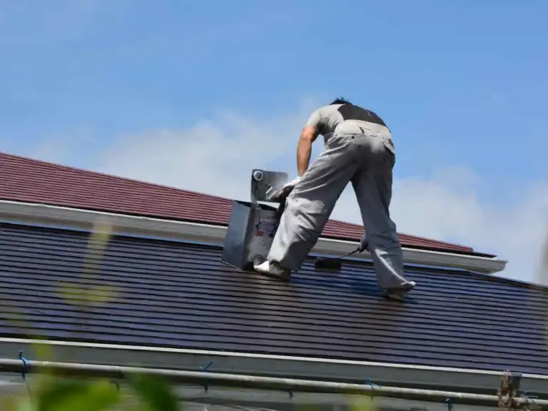 Worker on a metal roof preparing the surface for painting