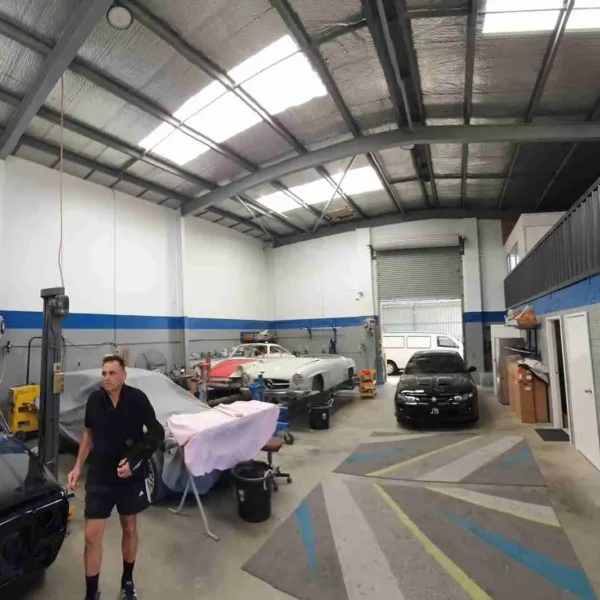Wide view of an auto repair workshop with cars and blue painted wall trim