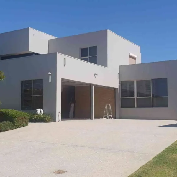 Exterior view of a modern two-story grey house with a wide concrete driveway