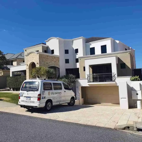 Multi-story modern white house exterior with a white van parked outside