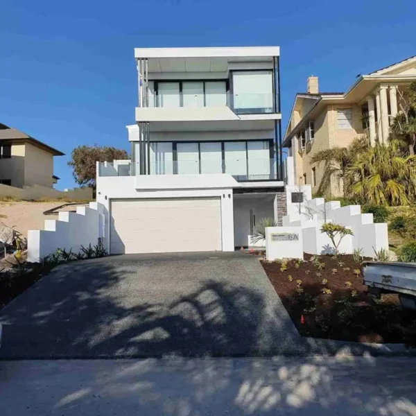 Modern white three-story house with balcony and paved driveway