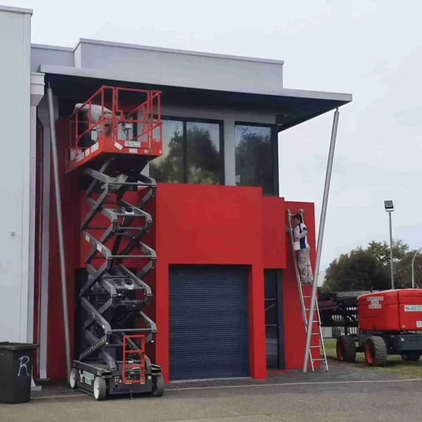 Red commercial building with scissor lift equipment outside