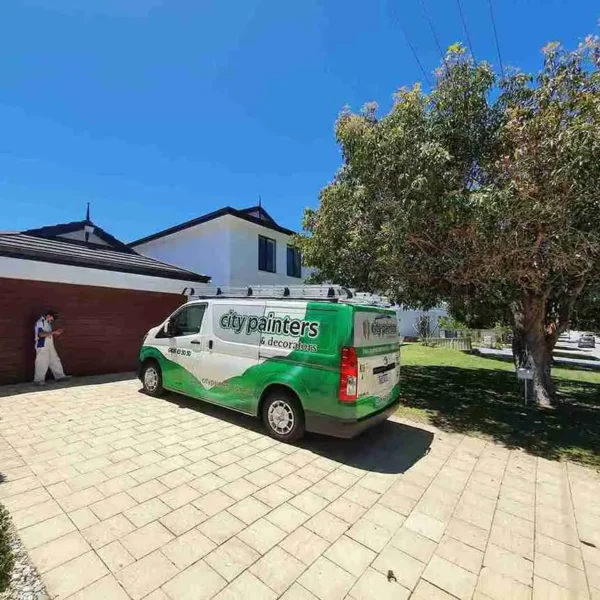 Green service van parked on a paved driveway in front of a house